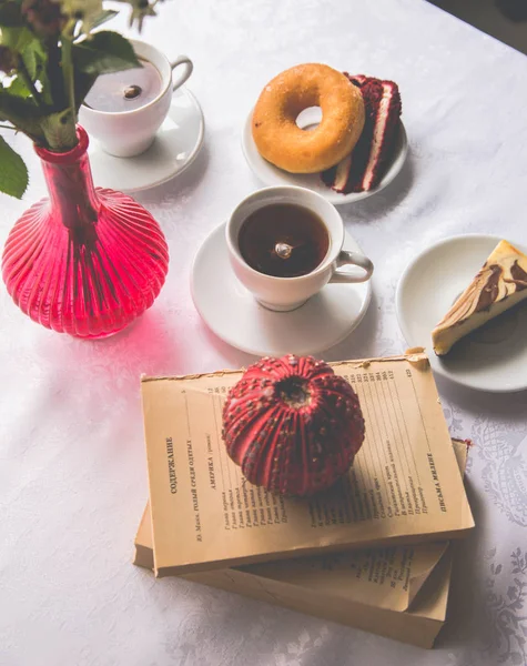 Primer plano que sirve platos en la mesa: té, donut, un pedazo de cak — Foto de Stock