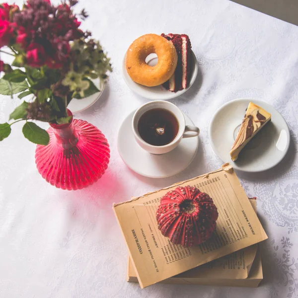 Close-up serving dishes on the table: tea, donut, a piece of cak