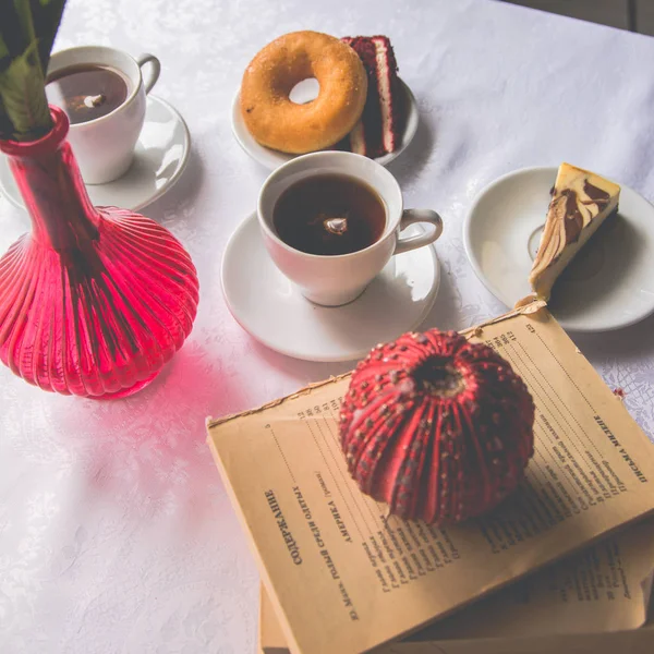 Primer plano que sirve platos en la mesa: té, donut, un pedazo de cak — Foto de Stock