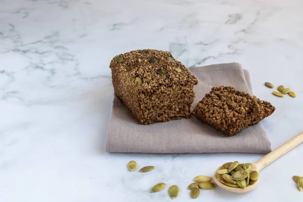 Gluten-free cereal bread with pumpkin seeds. Without flour, without yeast. Wooden spoon with pumpkin seeds. Horizontal orientation. Copy space.
