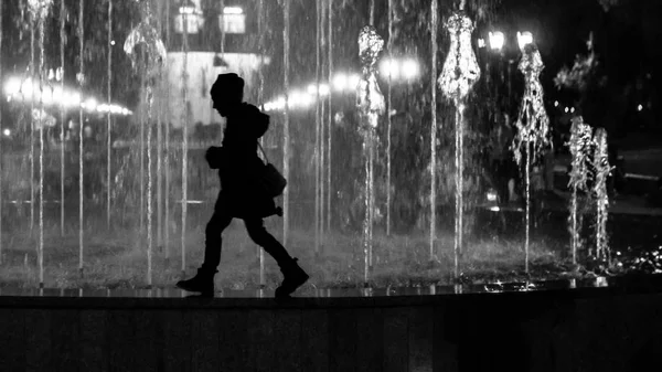 Çeşme sınırında yürüyen küçük bir kız çocuğu. Siyah ve beyaz siluet olarak biçimlendirilmiş