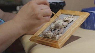 Kadın sanatçı vernik işleminden önce bir fırça ile el yapımı boyama temizlik