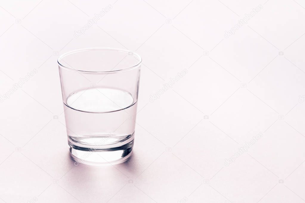 Half full glass of water. Abstract background.