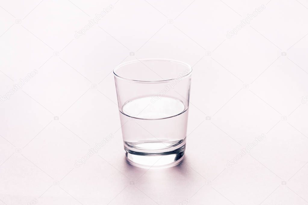 Half full glass of water. Abstract background.