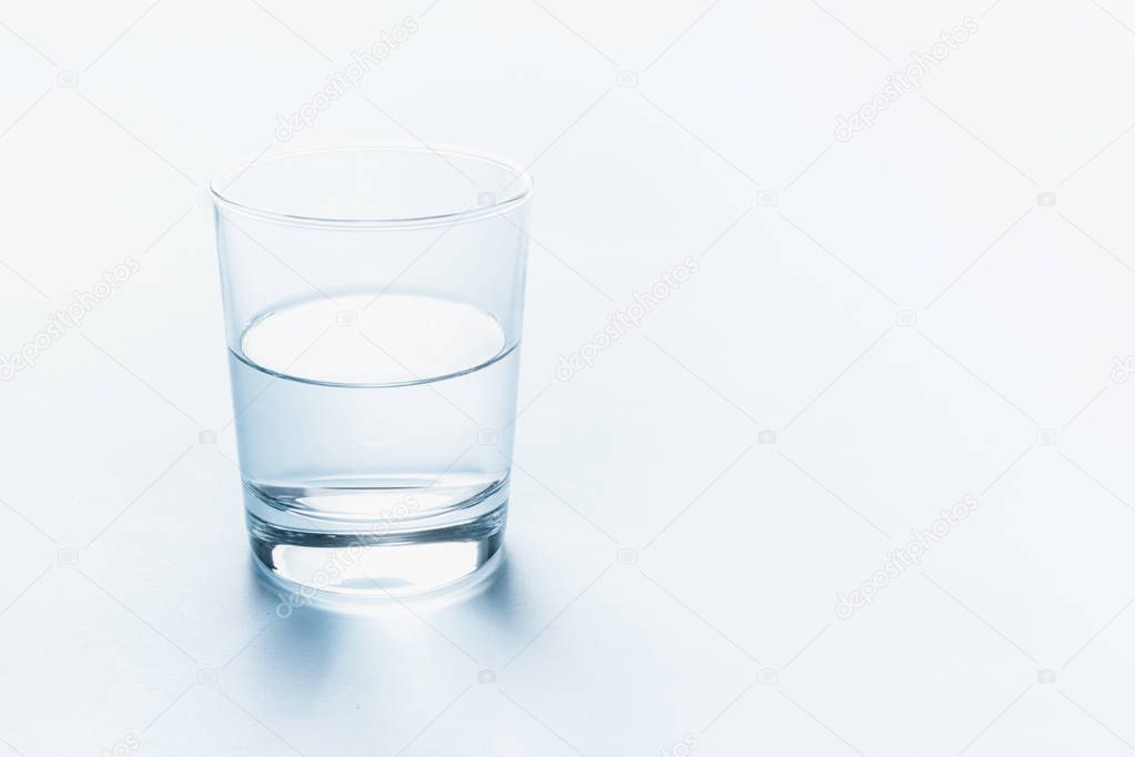 Half full glass of water. Abstract background.