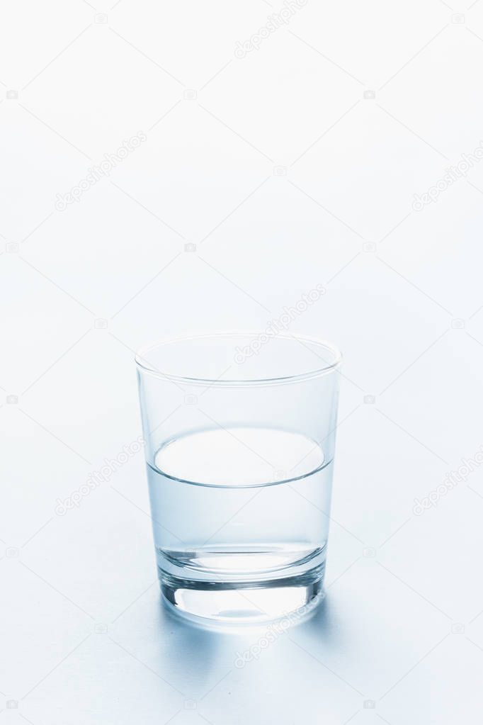 Half full glass of water. Abstract background.