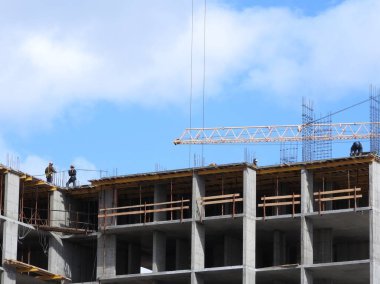 Büyük inşaat alanında, birkaç da dahil olmak üzere karmaşık bir açık mavi gökyüzü inşaat üzerinde çalışmaya vinç.