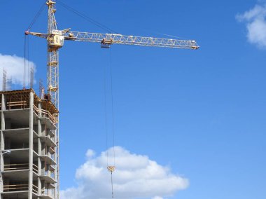 Büyük inşaat alanında, birkaç da dahil olmak üzere karmaşık bir açık mavi gökyüzü inşaat üzerinde çalışmaya vinç.
