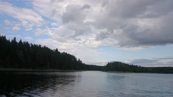 Modrá obloha a modré jezero v létě. Bílá oblaka se odráží ve vodě. Slavné jezero Seliger. Rusko. — Stock fotografie