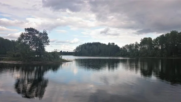 Синє небо та синє озеро влітку. Білі хмари відбиваються у воді. Знаменитий Селігер озера. Росія. — стокове фото