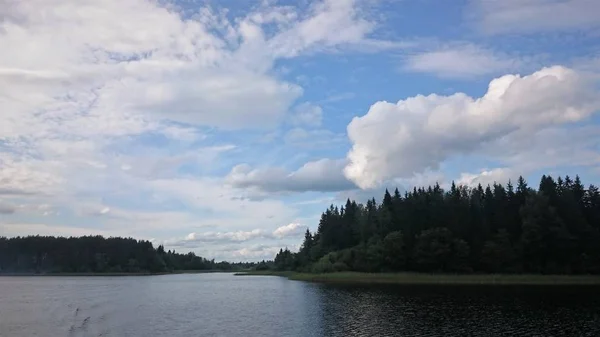 Синє небо та синє озеро влітку. Білі хмари відбиваються у воді. Знаменитий Селігер озера. Росія. — стокове фото