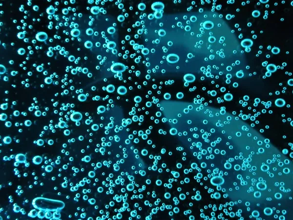 Close - up of air bubbles of different colors, in water isolated on dark background — Stock Photo, Image