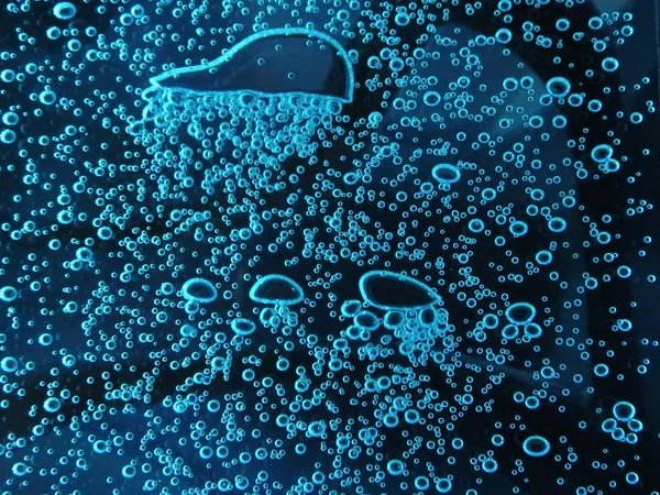 Закрытие - пузырьки воздуха разных цветов, в воде, изолированной на темном фоне — стоковое фото