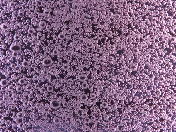 Nahaufnahme von Luftblasen in verschiedenen Farben, im Wasser isoliert auf dunklem Hintergrund — Stockfoto