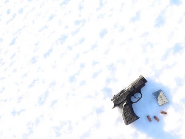 Uma arma de 9mm e uma bala com luvas espalhadas na neve . — Fotografia de Stock