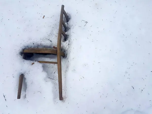 Vieille chaise avec rembourrage en tissu gelé dans la forêt dans la neige blanche . — Photo