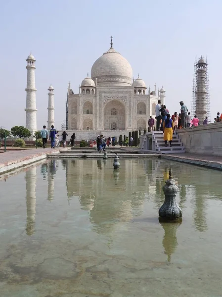 The girl in the hat from behind looks at the Taj Mahal Mausoleum, a symbol of love, white marble on the southern Bank of the Yamuna river in the Indian city of Agra, Uttar Pradesh. — Stock Photo, Image