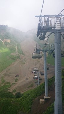 Dağ yamaçlarında teleferikler ve kayak pistleri ile bulutlu bir yaz günü, sis, bulutlar. Siyah piramit Dağı, Krasnaya Polyana, Soçi, Kafkaslar, Rusya.