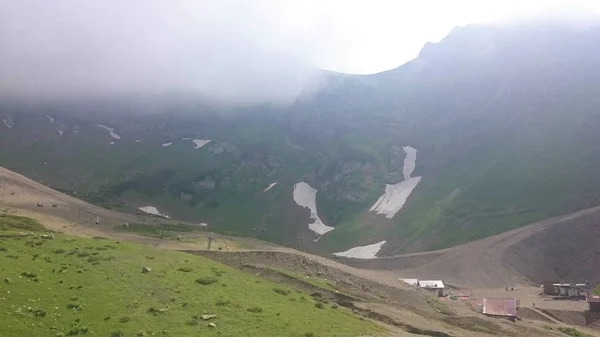 Panorama des montagnes et de la crête d'Aibga avec nuages bas. Restes de neige et d'herbe verte fraîche sur les montagnes près de la station de ski Rosa Khutor à Krasnaya Polyana. Sotchi, Russie . — Photo