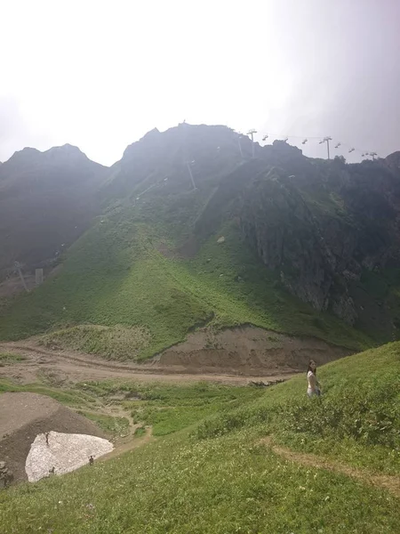 Panorama des montagnes et de la crête d'Aibga avec nuages bas. Restes de neige et d'herbe verte fraîche sur les montagnes près de la station de ski Rosa Khutor à Krasnaya Polyana. Sotchi, Russie . — Photo