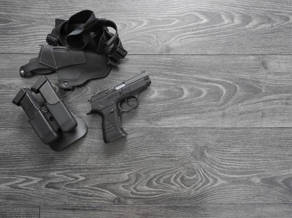 Gun black, spare magazines and leather holster on grey background.