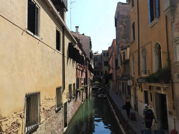 Piękna wenecka ulica, turyści idą z widokiem torby z tyłu, a kanały w letni dzień, Włochy. — Zdjęcie stockowe