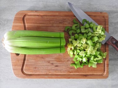 Taze yeşil kereviz, ahşap kesim tahtasının üzerine saplanır..