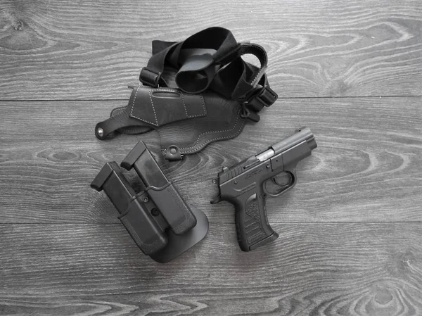 Gun preto, revistas de reposição e coldre de couro em fundo cinza . — Fotografia de Stock