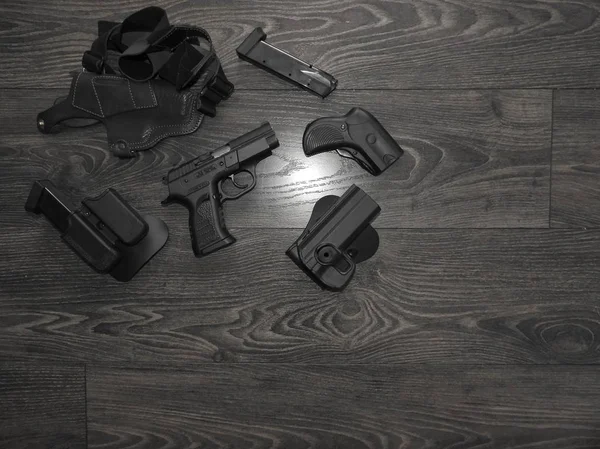 Pistolet noir, magazines de rechange et étui en cuir sur fond gris . Image En Vente
