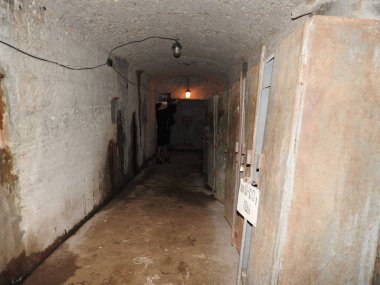 An abandoned prison in an underground bunker. A former Soviet cold war bomb shelter. The sealed door of the bunker. Pipes and valves. Low light condition. Bunker of fear and nightmares.