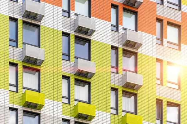 Multi-colored facade of modern multi-storey building, with compartments for installing air conditioners.