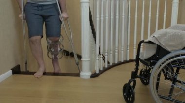 İlizarov'un dış fiksatifinde kırık bir bacakla koltuk değnekleriyle merdivenleri tırmanmak. Close. Tekerlekli sandalyedeki bir kişi..