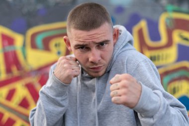 Kapüşonlu spor ceketli bir kabadayı.