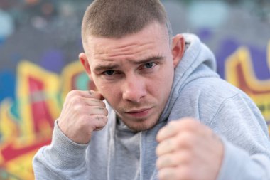 Kapüşonlu spor ceketli bir kabadayı.