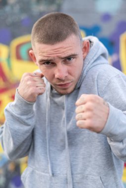 Kapüşonlu spor ceketli bir kabadayı.