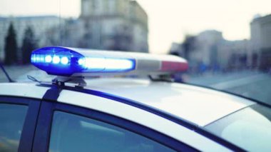 Polis teşhircisi devriye arabasının çatısında yanıp sönüyor.