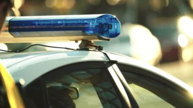 Polis teşhircisi devriye arabasının çatısında yanıp sönüyor.