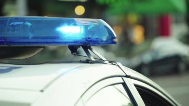 Polis teşhircisi devriye arabasının çatısında yanıp sönüyor.