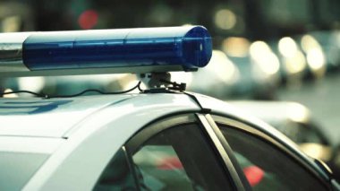 Polis teşhircisi devriye arabasının çatısında yanıp sönüyor.