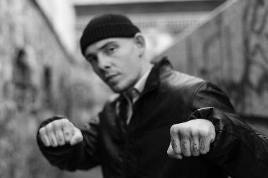 Kabadayı bir adamın kolunda ACAB dövmesi var. Siyah beyaz fotoğraf