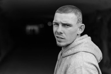 Açık renk spor ceketli, kapüşonlu bir kabadayı. Siyah beyaz fotoğraf. BW