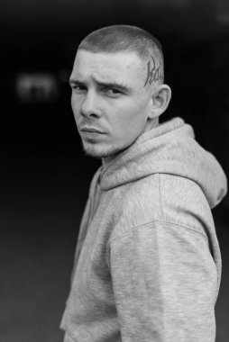 Açık renk spor ceketli, kapüşonlu bir kabadayı. Siyah beyaz fotoğraf. BW