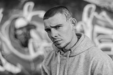 Açık renk spor ceketli, kapüşonlu bir kabadayı. Siyah beyaz fotoğraf. BW