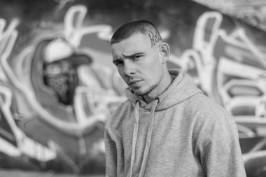 Açık renk spor ceketli, kapüşonlu bir kabadayı. Siyah beyaz fotoğraf. BW