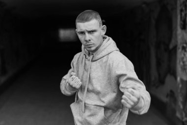 Açık renk spor ceketli, kapüşonlu bir kabadayı. Siyah beyaz fotoğraf. BW