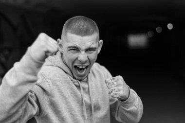 Açık renk spor ceketli, kapüşonlu bir kabadayı. Siyah beyaz fotoğraf. BW