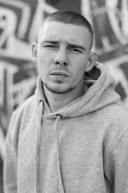 Açık renk spor ceketli, kapüşonlu bir kabadayı. Siyah beyaz fotoğraf. BW