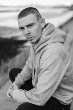 Açık renk spor ceketli, kapüşonlu bir kabadayı. Siyah beyaz fotoğraf. BW