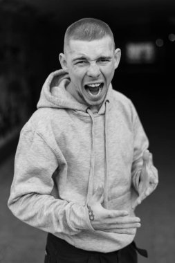 Açık renk spor ceketli, kapüşonlu bir kabadayı. Siyah beyaz fotoğraf. BW