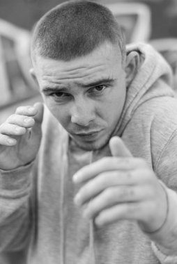 Açık renk spor ceketli, kapüşonlu bir kabadayı. Siyah beyaz fotoğraf. BW